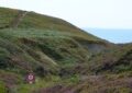 Scenic view of grassy hills leading to the ocean in Camaret-sur-Mer, France.