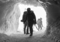 Mountaineers in silhouette exiting an ice cave, Chamonix, France.