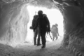 Mountaineers in silhouette exiting an ice cave, Chamonix, France.