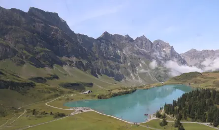 Turquoise lake surrounded by green hills and mountains.