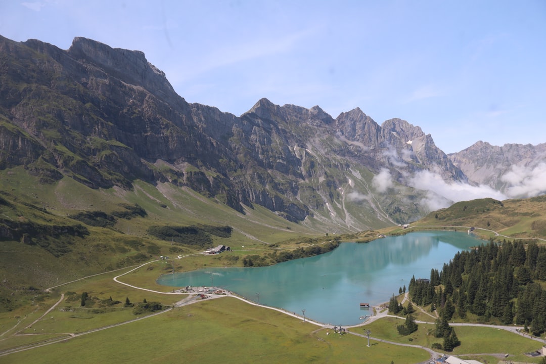 Turquoise lake surrounded by green hills and mountains.