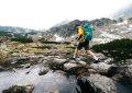 a man with a backpack is crossing a stream