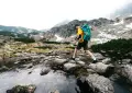 a man with a backpack is crossing a stream