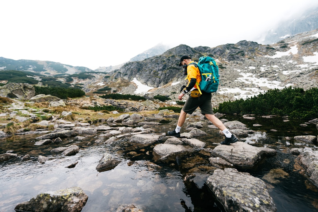 a man with a backpack is crossing a stream