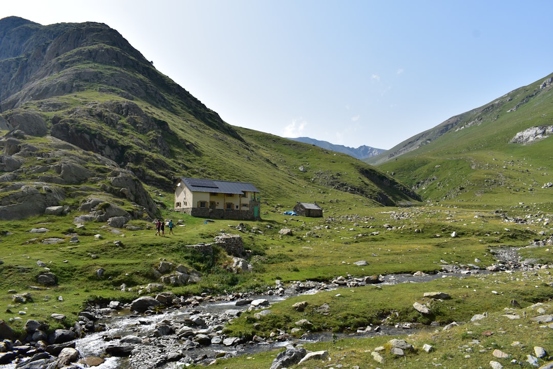 white and brown house on green grass field near mountain during daytime