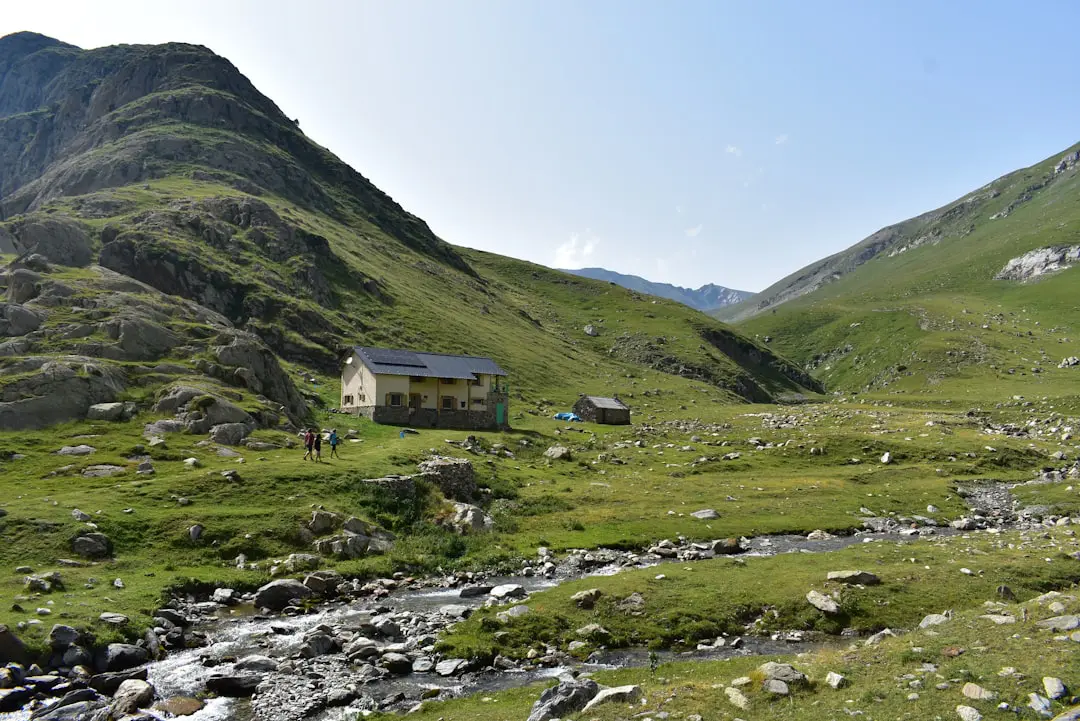 white and brown house on green grass field near mountain during daytime