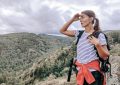 a woman standing on top of a mountain with a backpack