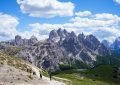 Hikers on a mountain path under a cloudy sky.