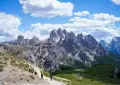 Hikers on a mountain path under a cloudy sky.