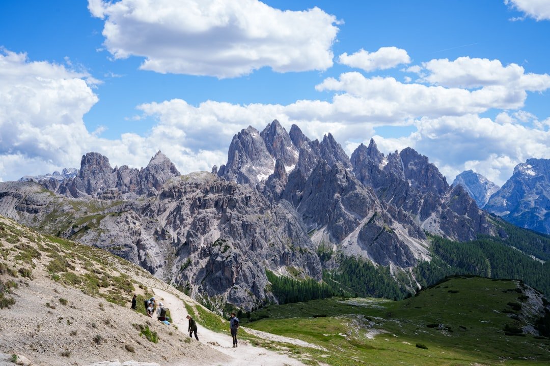 Hikers on a mountain path under a cloudy sky.